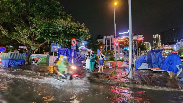 Một số người chọn đứng lại trên vỉa hè, chờ nước rút thay vì đi qua khu vực ngập.