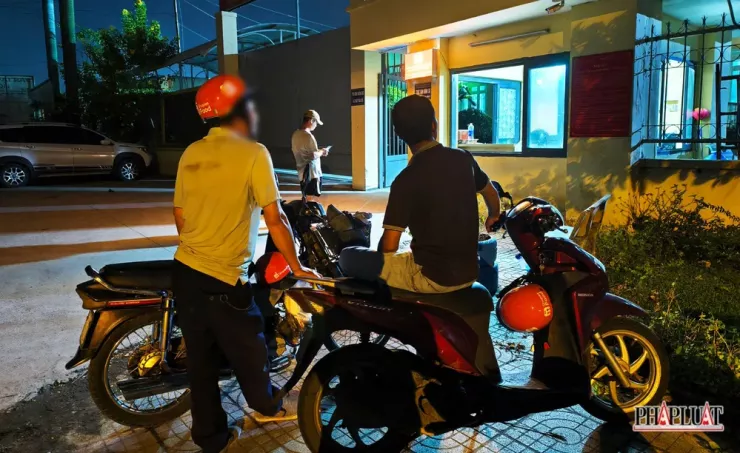 Anh L đứng chờ cùng với hai tài xế xe ôm đã giúp đỡ gia đình trước trụ sở Công an phường An Phú Đông để nhận con. Ảnh: NT