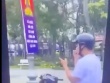Nam thanh niên đi xe máy thả hai tay vừa xem điện thoại, vừa xỉa răng