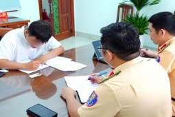 Nam thanh niên đi xe máy thả hai tay vừa xem điện thoại, vừa xỉa răng