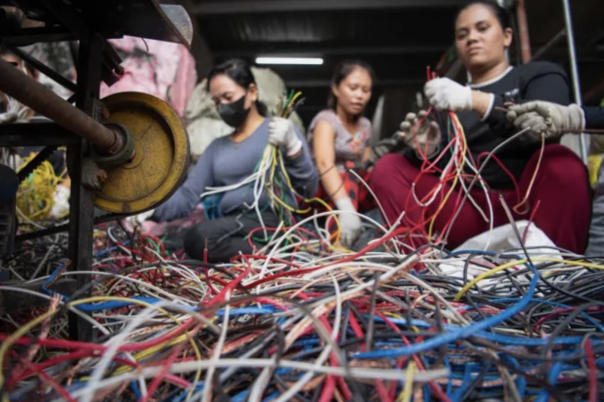 Người dân đang bóc dây điện để lấy lõi đồng trong một xưởng tái chế ở Manila. Ảnh: AFP/ TED ALJIBE