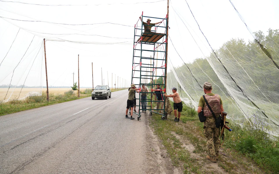 Binh sĩ Ukraine cố gắng dựng lưới chắn UAV ở tuyến đường huyết mạch. Ảnh: Telegraph.