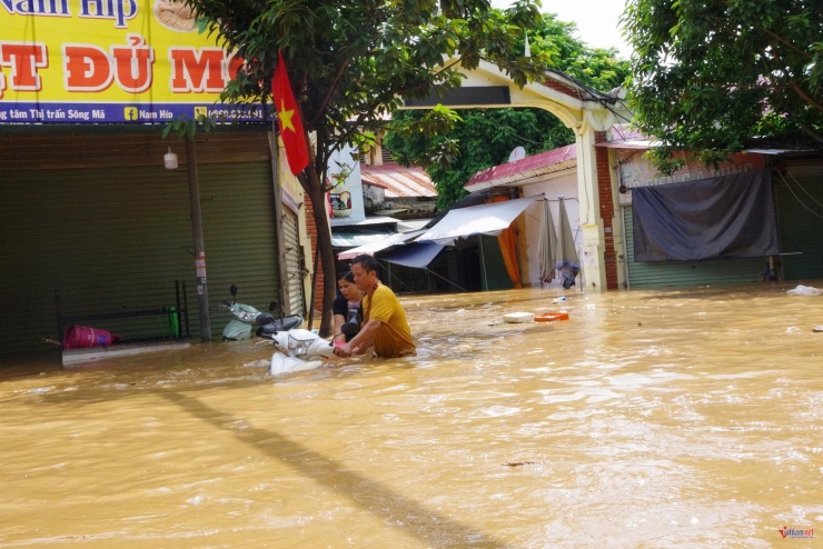 Người dân bì bõm di chuyển phương tiện giữa dòng nước lũ. Ảnh: Nguyễn Nam