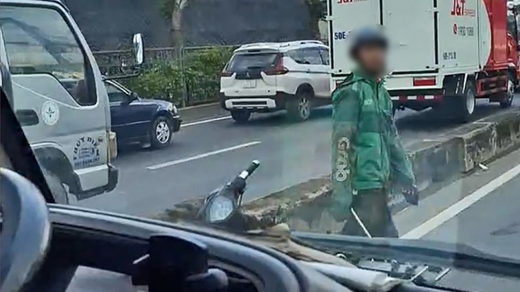 Nam thanh niên sau đó chặn đường, cầm cây sắt đập vỡ kính chiếu hậu xe tải. Ảnh: Cắt từ clip