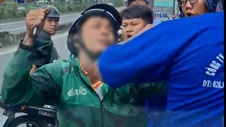 Người thanh niên mặc áo xe ôm công nghệ cầm một vật gì đó trong tay tấn công tài xế ô tô tải. Ảnh: Cắt từ clip
