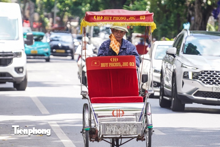 Một người lái xích lô liên tục dùng khăn lau mồ hôi giữa trưa nắng gắt.