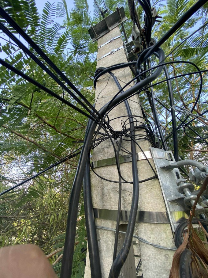 Cột điện cạnh nhà ông Tâm chằng chịt dây điện và cáp viễn thông. Ảnh: Gia đình cung cấp