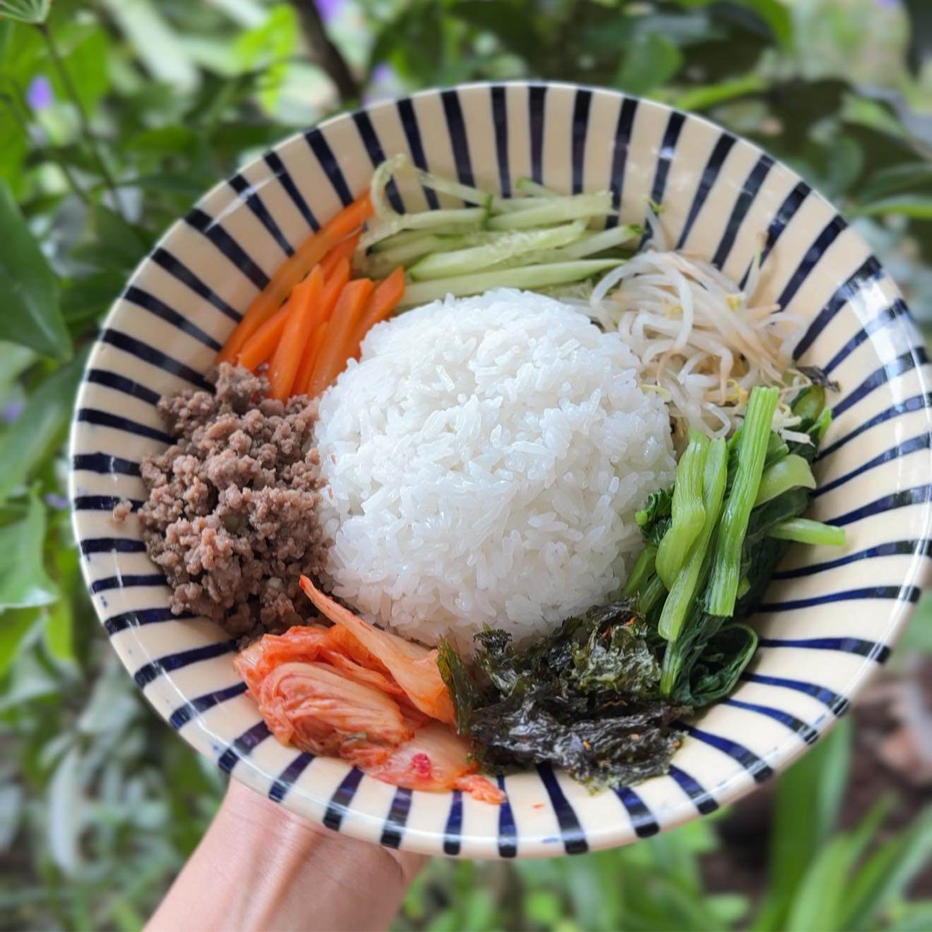 Cho cơm vào tô, xếp rau củ, thịt bò, kim chi và trứng ốp la vào.