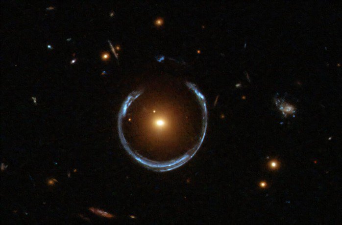 Hệ thống thấu kính hấp dẫn Cosmic Horseshoe với thiên hà thấu kính màu cam và một "vành đai Einstein". Lỗ đen quái vật vừa được phát hiện nằm bên trong thiên hà màu cam - Ảnh: NASA/ESA