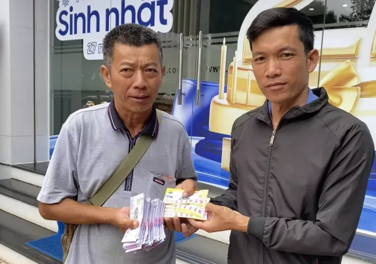 Ông Nguyên (bìa phải) trả lại 60 tờ vé số cho người đánh rơi. Ảnh: N.V