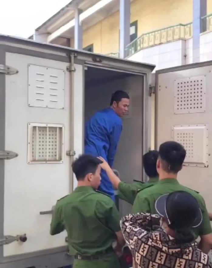 Bị cáo Thái Khắc Thành quay đầu lại nhìn vợ ôm con nhỏ đứng khóc tiễn chồng lên xe thùng về trại tạm giam sau khi tòa sơ thẩm tuyên án