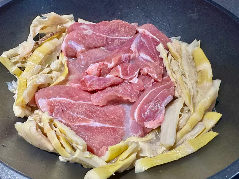 Thêm thịt heo, đảo đều. Rưới dầu hào lên, đảo để thịt và măng ngấm đều gia vị. Thêm&nbsp;250ml nước lọc, nếu muốn vị cay nhẹ thì thêm nửa&nbsp;thìa tương ớt.