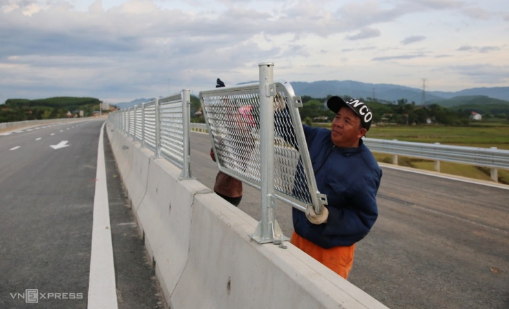 Những đoạn hàng rào chống chói được lắp trước ngày thông xe. Sơn kẻ đường, đường gom đang được hoàn tất. Công nhân cũng xịt rửa trôi bùn đất bám trên mặt đường do xe di chuyển trong quá trình thi công.
