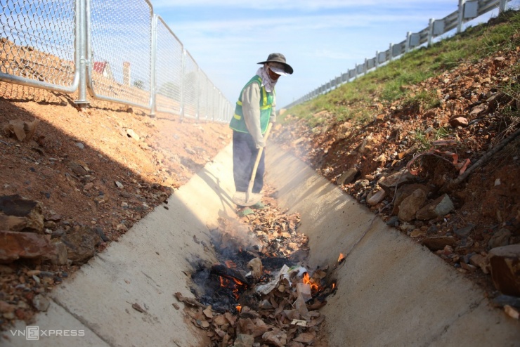 Công nhân đang thu gom rác và dọn dẹp mương thoát nước dọc tuyến cao tốc. Hai bên đường, lưới sắt và thép gai đã được lắp đặt hoàn chỉnh, chỉ còn một vài đoạn cầu dân sinh, mương thoát nước và đường gom đang trong giai đoạn hoàn thiện cuối cùng.