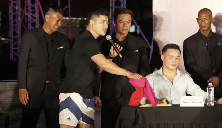 Ngọc Thức (áo đen) gửi Tiến Long (áo trắng) bộ váy dành tặng cho Trung Hải, người vắng mặt trận này 