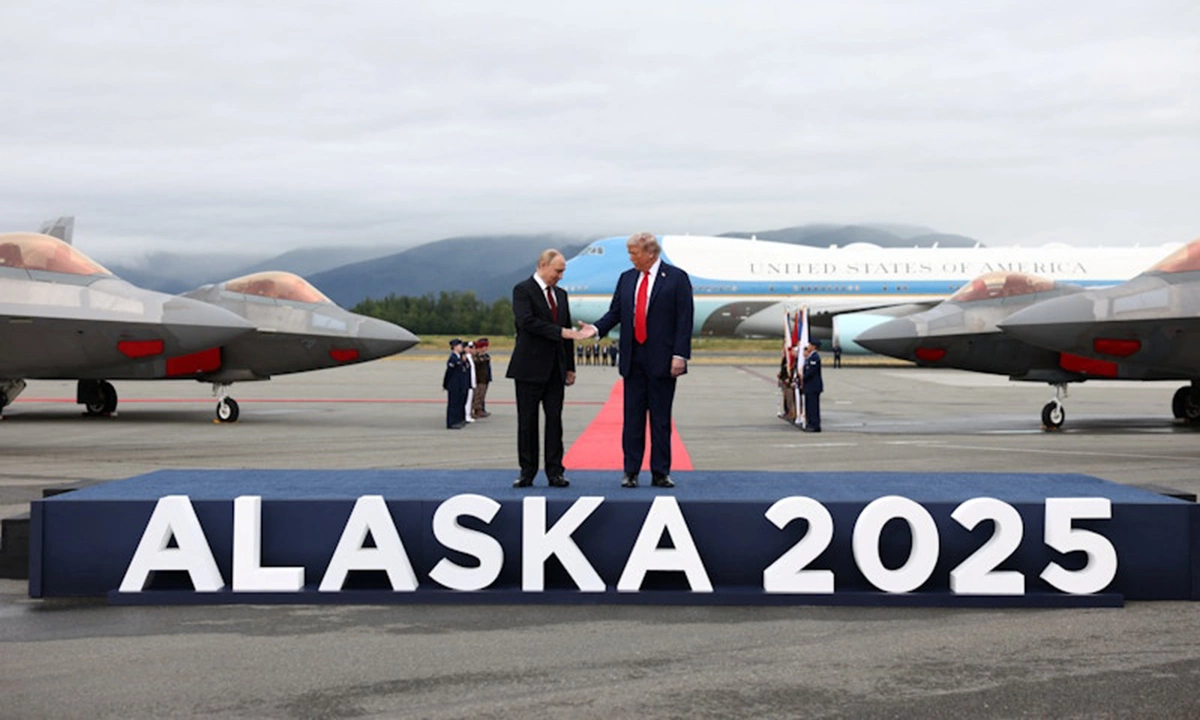 Ông Trump và ông Putin bắt tay nhau trên bục. Phía bên cạnh là các tiêm kích tàng hình F-22. Ảnh: Reuters.