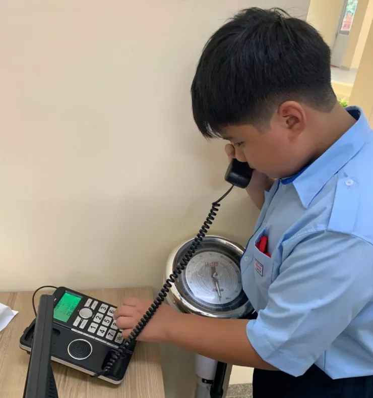 Học sinh Trường THCS Nguyễn Thái Bình sử dụng điện thoại bàn gọi điện về cho gia đình. Ảnh: NTCC