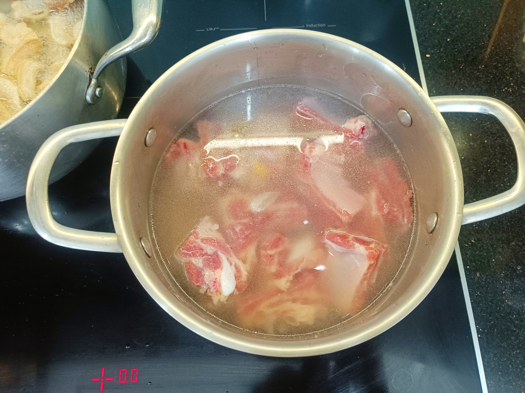 Chần sườn trong nồi nước có thêm miếng gừng, hành khô đập dập. Vớt sườn ra, rửa lại bằng nước lạnh rồi để ráo.