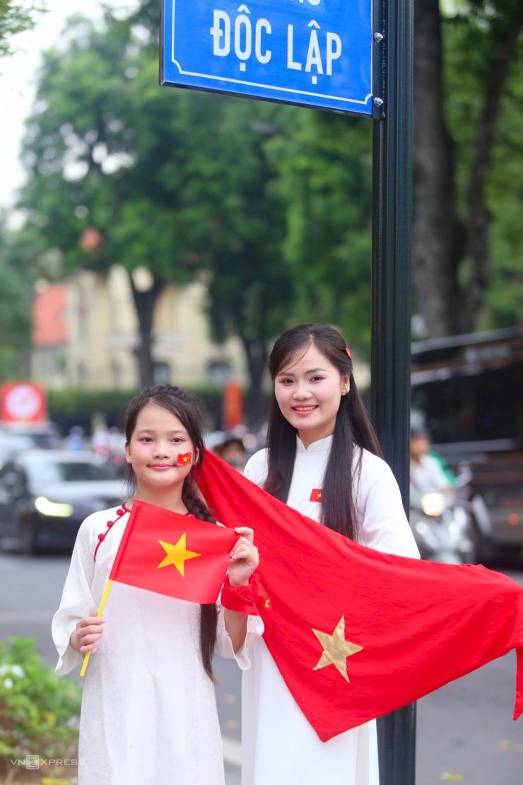 Hai mẹ con tranh thủ diện áo dài chụp ảnh với cờ Tổ quốc trên đường Độc Lập, phường Ba Đình.