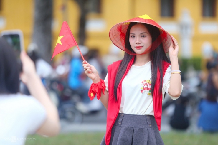 Bạn trẻ mang nón lá, sticker chụp hình lưu niệm trên đường. Do cấm đường từ 11h30, người dân muốn tiếp cận gần đoàn diễu binh, diễu hành phải lên phố từ trước đó.