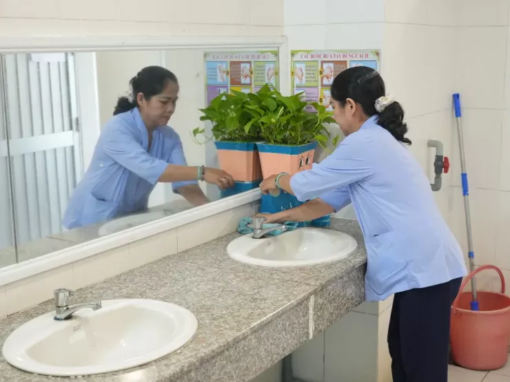 Nhân viên Trường Tiểu học Võ Trường Toản lau chùi khu vực nhà vệ sinh. Ảnh: QUỐC VŨ