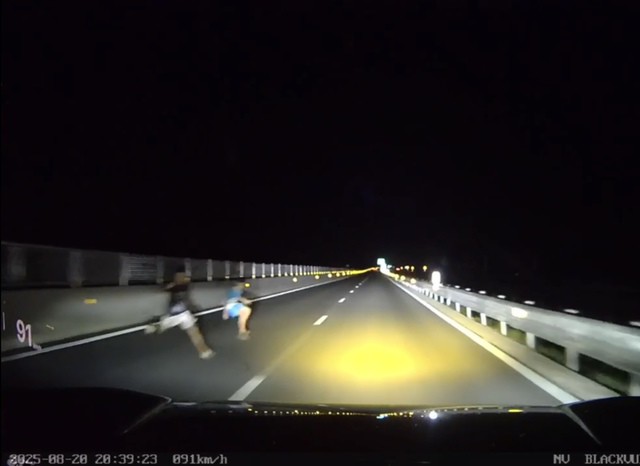 Cảnh 2 người lao ra từ giải phân cách cao tốc. (Ảnh cắt từ video).