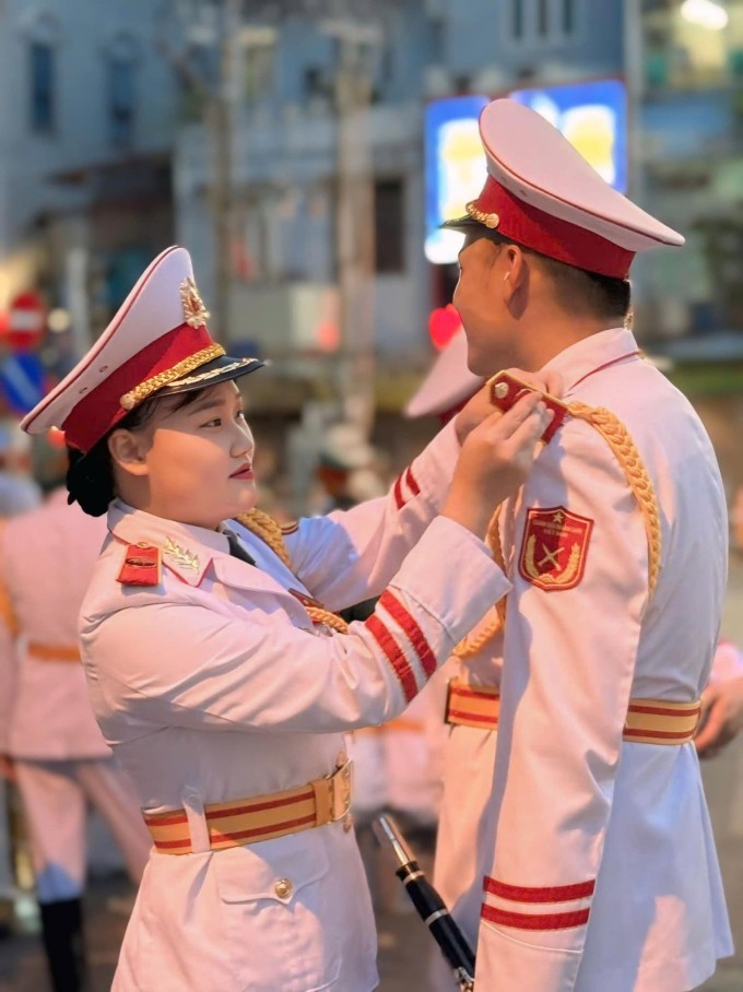 Chiến sĩ Nguyễn Thị Phương Thanh chỉnh lại trang quân trang cho chồng, anh Dương Thanh Bình, 30 tuổi, công tác tại Đoàn Nghi lễ Quân đội, chiều tối 21/8 trên phố Ngọc Hà. Ảnh: Nhân vật cung cấp