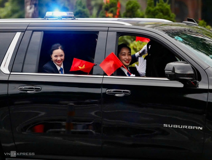 Nữ cảnh vệ mang sticker cờ Tổ quốc, giơ tay chào người dân ven đường. Ảnh: Hiếu Lương