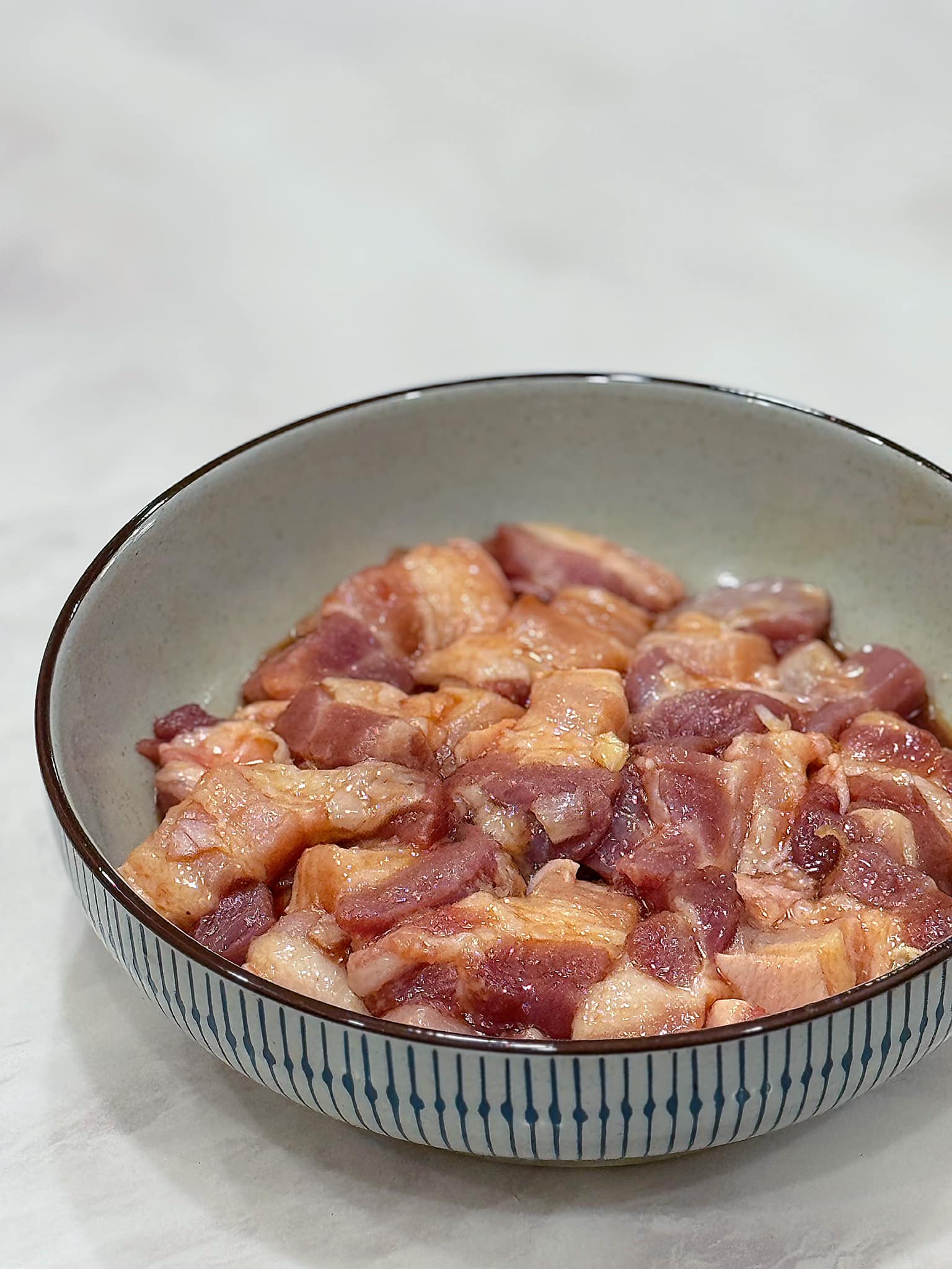 Thịt ba chỉ thái miếng, ướp khoảng 30 phút với 2 thìa cà nước mắm, 2 thìa hạt nêm, 2 củ hành băm, 1 củ tỏi đập dập, 3 thìa cà phê nước hàng.
