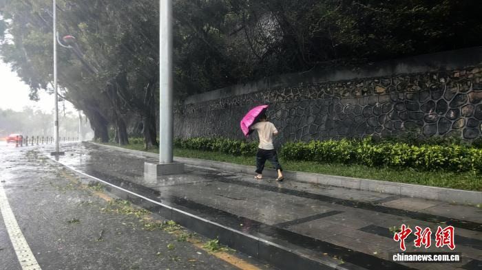 Người dân che ô, đi lại khó khăn do ảnh hưởng của bão số 5 ở thành phố Tam Á, đảo Hải Nam, Trung Quốc. Ảnh: CNS