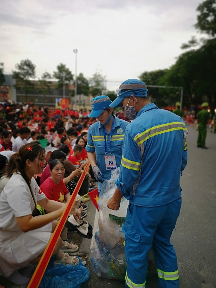 Nhân viên vệ sinh môi trường đến tận nơi người dân xem diễu binh thu gom rác.
