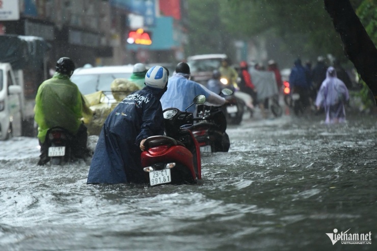 Nước ngập sâu lút bánh xe máy trên phố Đội Cấn, người dân chật vật di chuyển.
