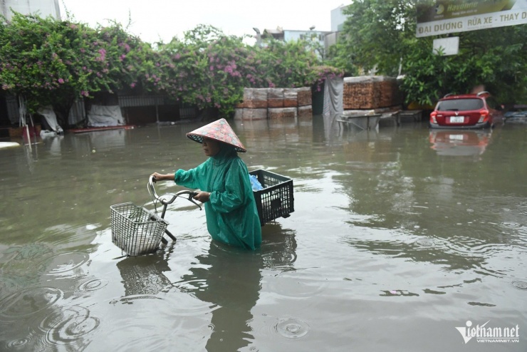 Lội quãng ngập dài tới bụng, bà Nga cho biết bà làm công việc nấu cơm cho thợ nên hôm nay vẫn phải tới nơi làm việc. Bà vừa đi chợ về, than thở: "Giá rau củ tăng đột biến trong hôm nay".