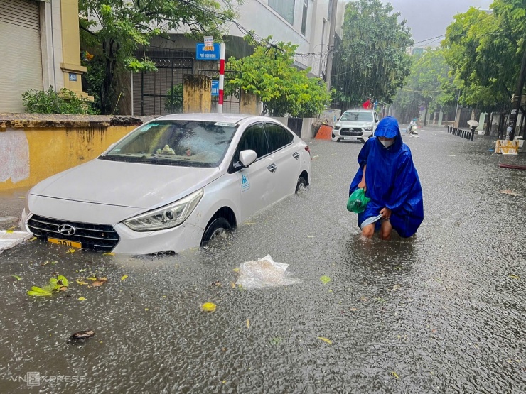 Nước ngập tới đầu gối ở phố Dịch Vọng, Cầu Giấy khiến người dân đi lại khó khăn. Ảnh: Lê Gạch