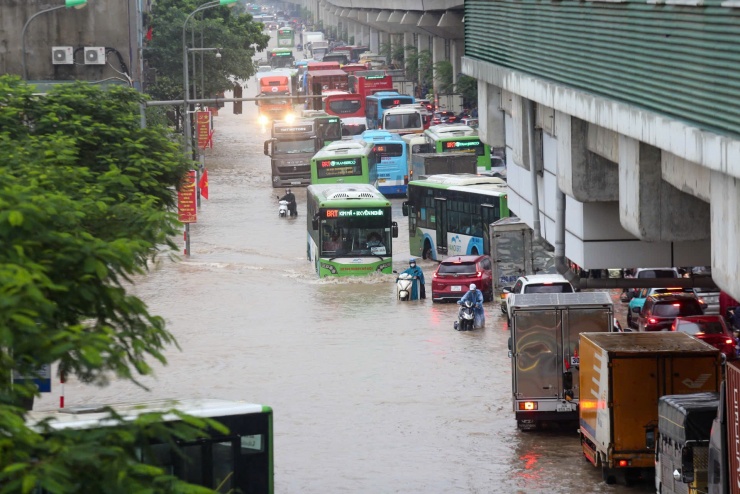 Trước bến xe Yên Nghĩa nước ngập kéo dài khoảng một km, vị trí sâu nhất hơn nửa mét, cảnh sát đứng ở đầu đường đề nghị các xe gầm thấp chuyển hướng. Ảnh: Gia Chính