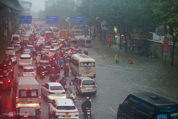 Giao thông tê liệt trên đường Nguyễn Trãi ở cả hai hướng do một số đoạn nước ngập sâu tới nửa mét. Nhân viên môi trường phải cắm biển thoát nước. Ảnh: Phạm Chiểu