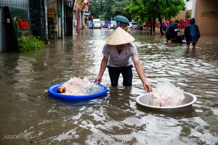 Người đàn ông dùng chậu chở đồ ăn qua đoạn đường ngập nước ở Mỹ Đình. Ảnh: Tùng Đinh