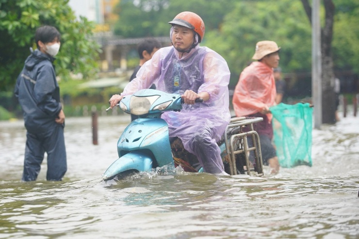Đường và hồ &#39;hòa làm một&#39; sau mưa lớn, người dân lấy cọc làm mốc để lội về nhà - 7