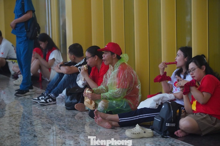 Khán giả vạ vật chờ đợi trong cơn mưa lớn. Các khu vực có mái che trong khuôn viên Trung tâm Triển lãm Quốc gia chật kín người. Dù đã chuẩn bị áo mưa, ô, nhưng dưới cơn mưa lớn, nhiều người vẫn chọn trú dưới mái che.