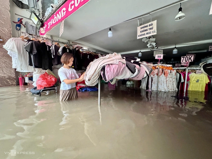 Chị Xua dọn những bộ đồ chưa ngấm nước. Ảnh: Anh Phú