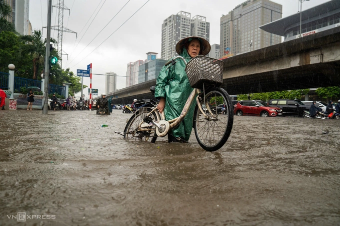 Người dân phải vác xe đạp do nước ngập quá sâu. Ảnh: Đình Tùng