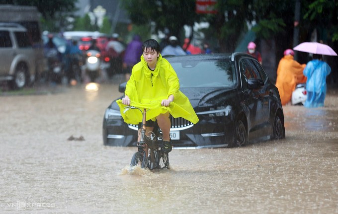 Một người dân vác xe đạp qua đoạn ngập. Video: Anh Phú