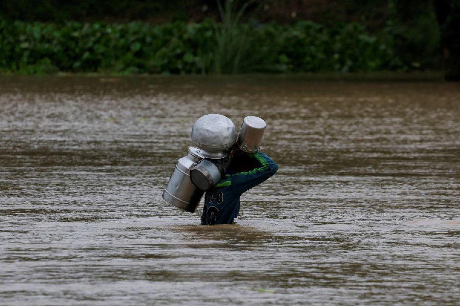 Người đàn ông ở Punjab vác theo bình đựng sữa băng qua đoạn đường ngập nặng do nước sông Sutlej dâng cao (ảnh: Reuters)
