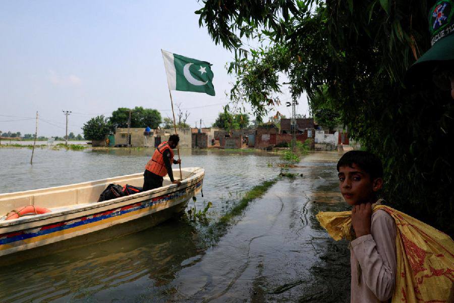 Trẻ em ở Punjab mang theo bao tải đựng nhu yếu phẩm lên xuồng cứu hộ (ảnh: Reuters)