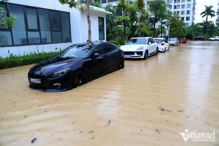 Nước ngập ngang bánh xe, chạm gần tới mép cửa các ô tô dừng đỗ ven đường tại khu đô thị. Ảnh: Phạm Công