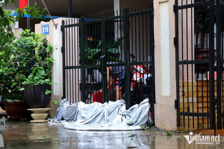 Một người dân che chắn cổng để ngăn không cho nước tràn vào nhà. Ảnh: Phạm Công