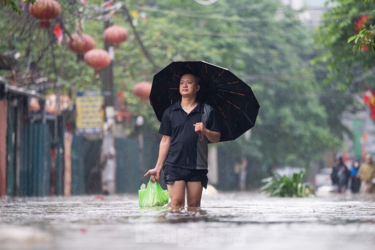Lượng nước rút chậm khiến việc di chuyển gặp nhiều khó khăn, người dân phải lội bộ giữa dòng nước ngập để về nhà.