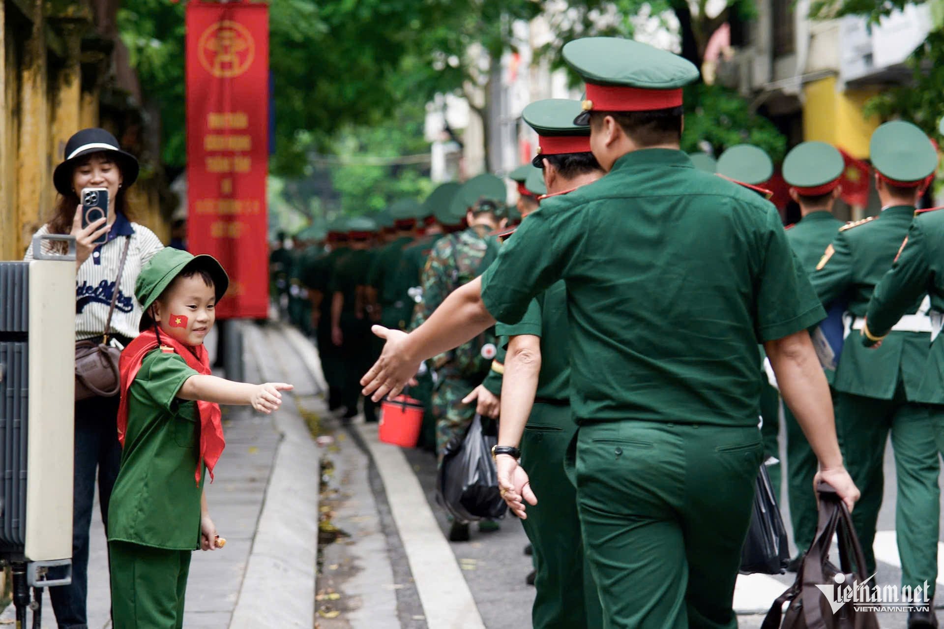 Em nhỏ trong trang phục quân đội hào hứng bắt tay các chú bộ đội. Ảnh: Huy Anh