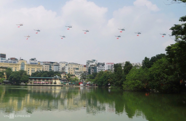 Trước đó, biên đội trực thăng10 chiếc gồm Mi-171, Mi-17, Mi-8 mang cờ Tổ quốc, cờ Đảng cất cánh từ sân bay Hòa Lạc qua khu vực hồ Gươm. Ảnh: Võ Thạnh