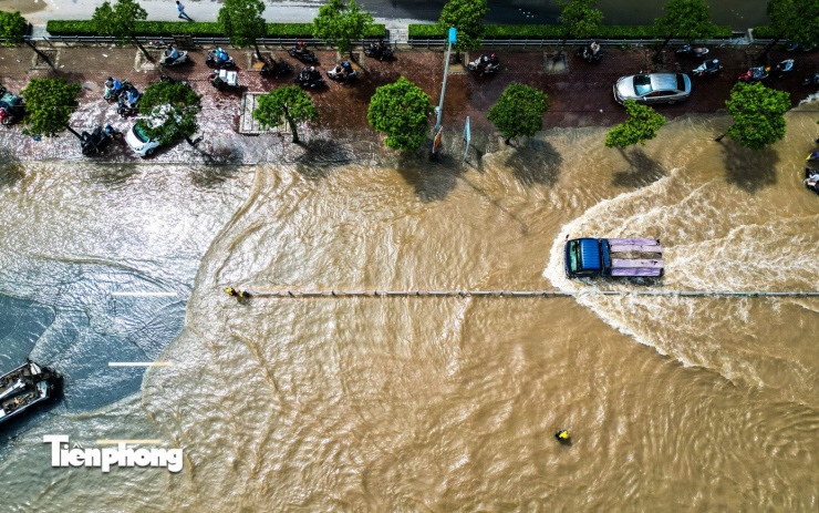 Hàng dài ô tô, xe máy nối đuôi nhau leo lên vỉa hè để tránh đoạn ngập sâu.
